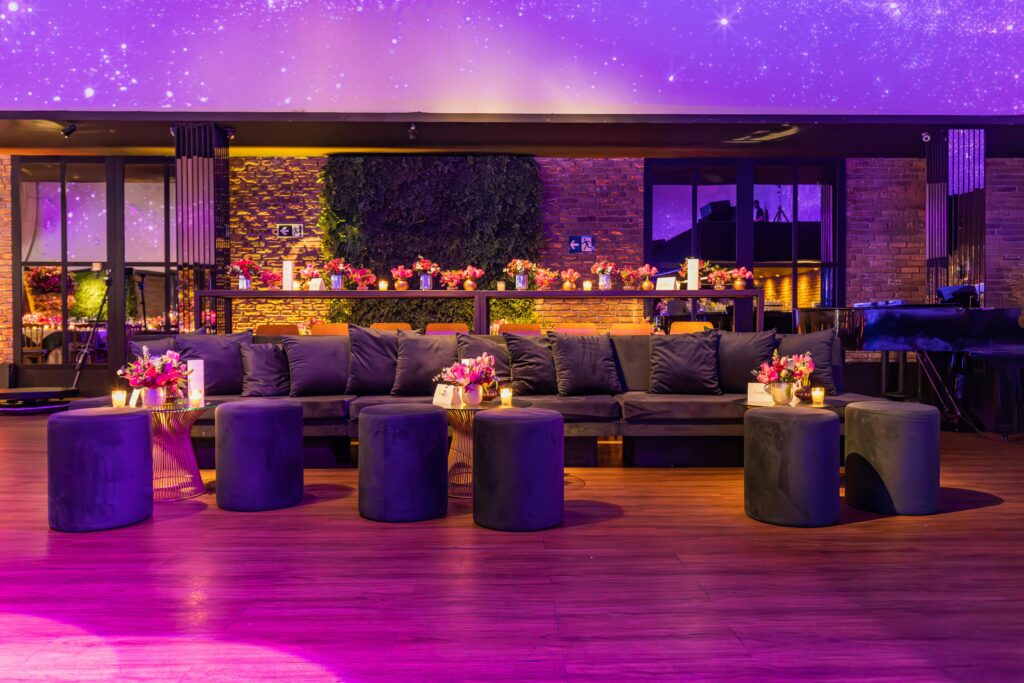 Luxurious event setting with plush seating, floral decor, and mood lighting in a modern lounge.